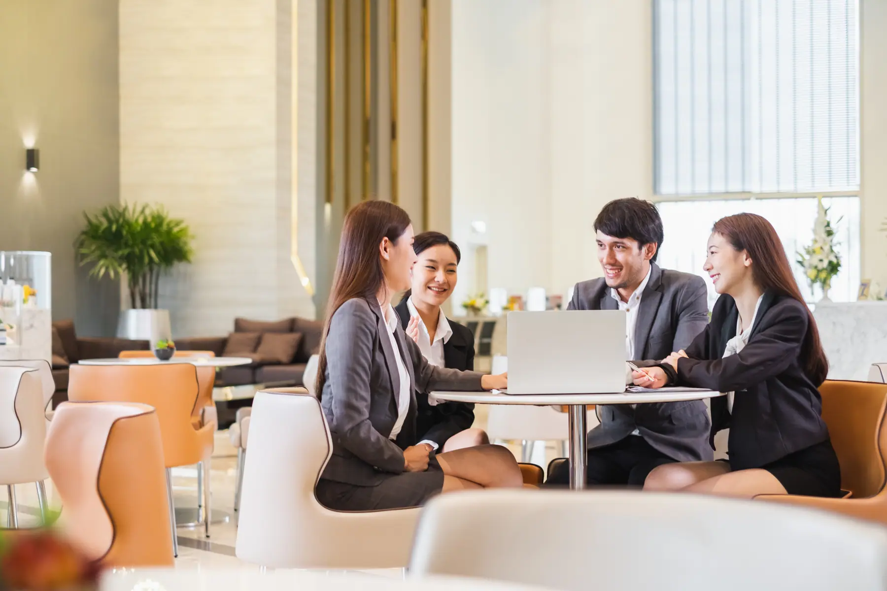 Team meeting with laptops in a bright office lounge